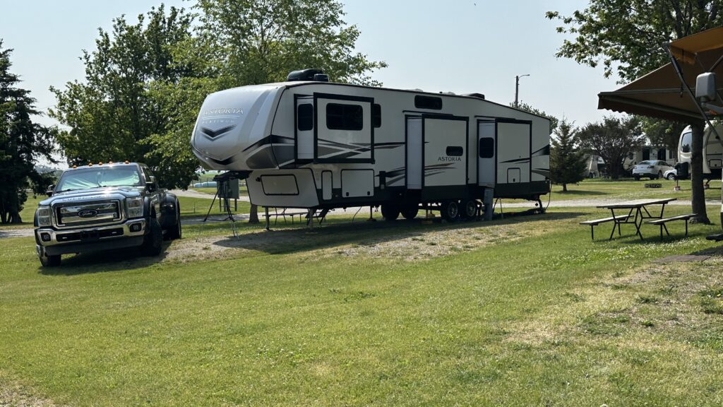 Our fifth wheel parked on grass with our F-450 pickup parked at an angle in front of it.